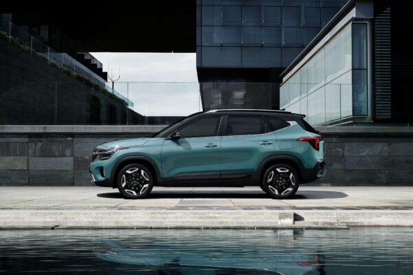 A sleek green SUV parked in front of a contemporary building beside a water feature.