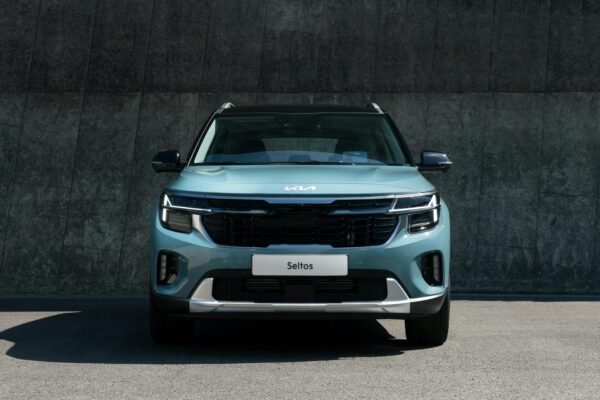 A modern blue Kia Seltos SUV parked against a concrete wall in daylight.